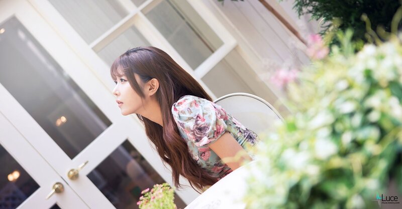woman in floral dress by window