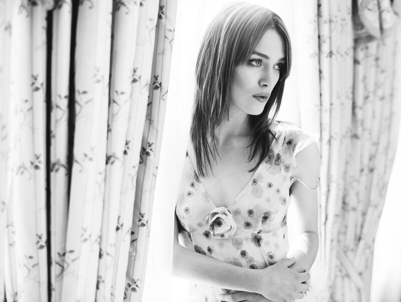 woman in floral dress by window