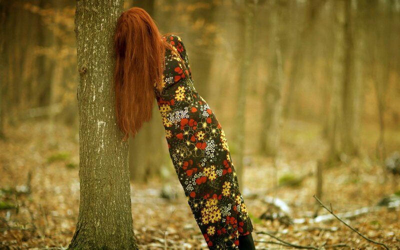 woman in floral dress leaning on tree