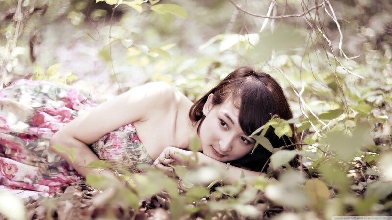 woman in floral dress lying in forest