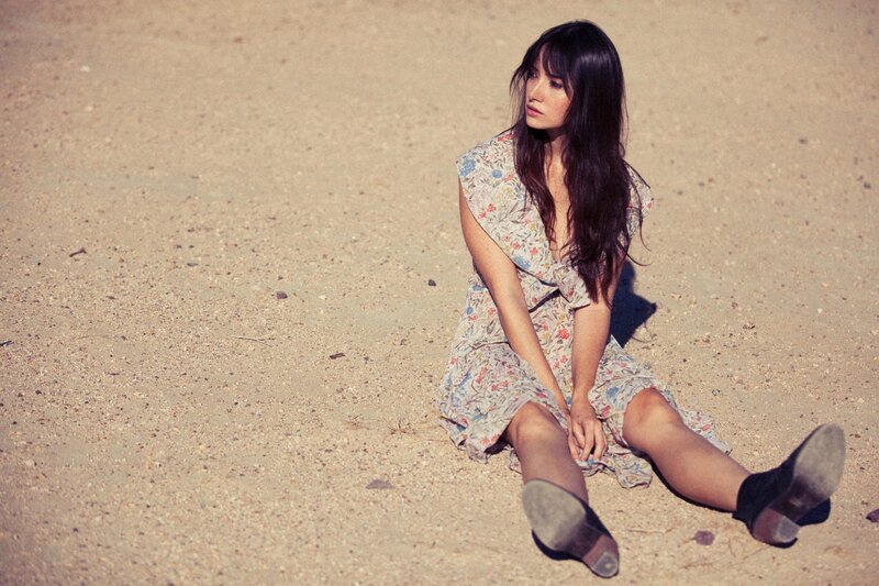 woman in floral dress sitting on sand