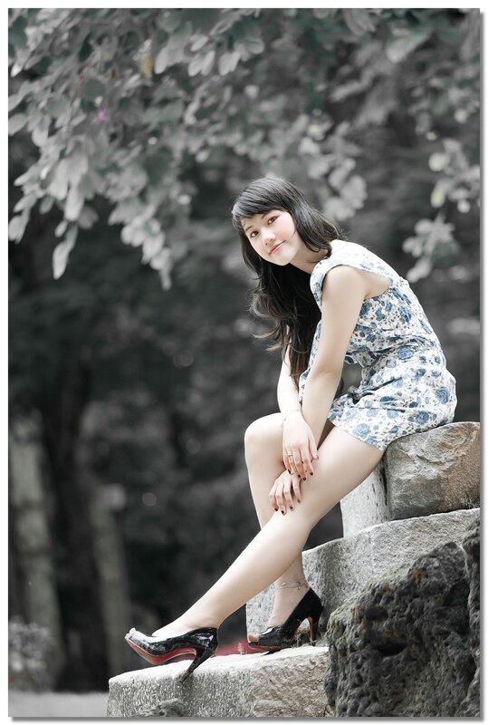 woman in floral dress sitting on stone