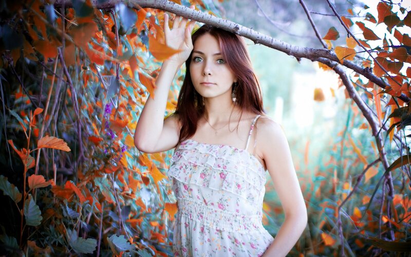 woman in floral dress under autumn leaves
