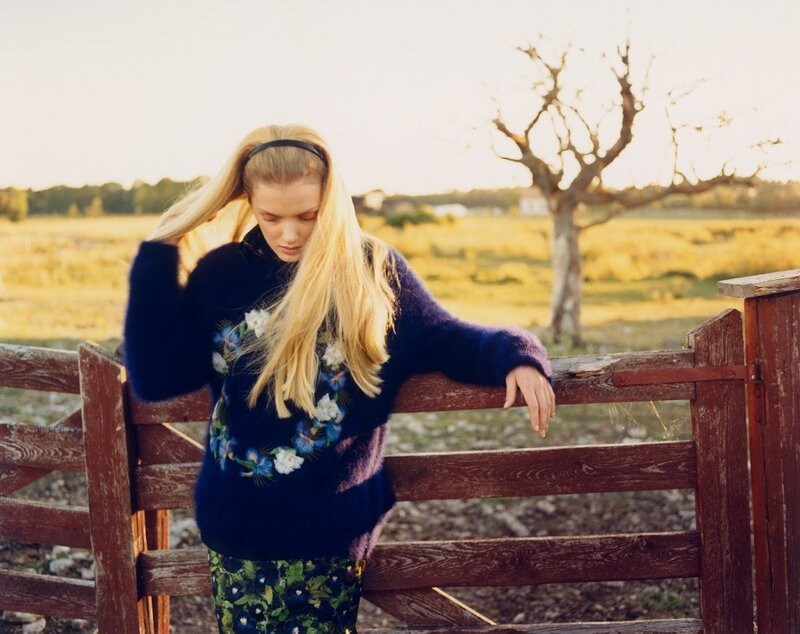 Woman in floral sweater by fence