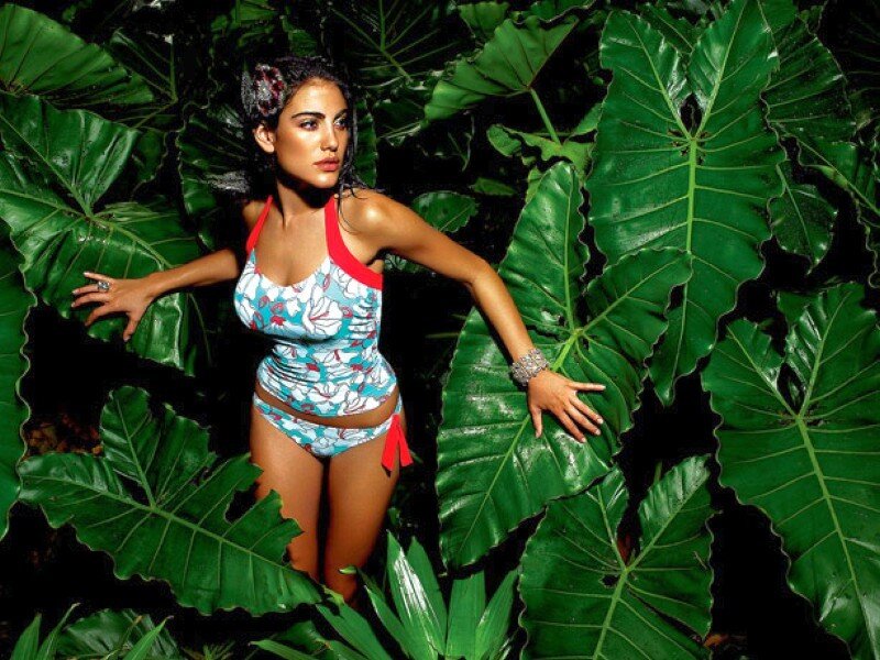 Woman in floral swimsuit among tropical leaves