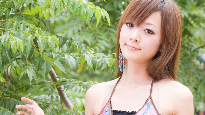woman in floral top by green leaves