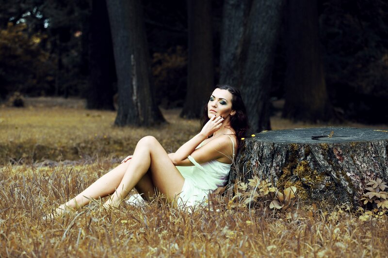 Woman in forest by tree stump