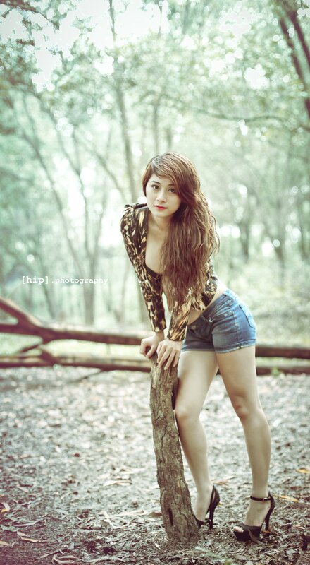 woman in forest leaning on tree