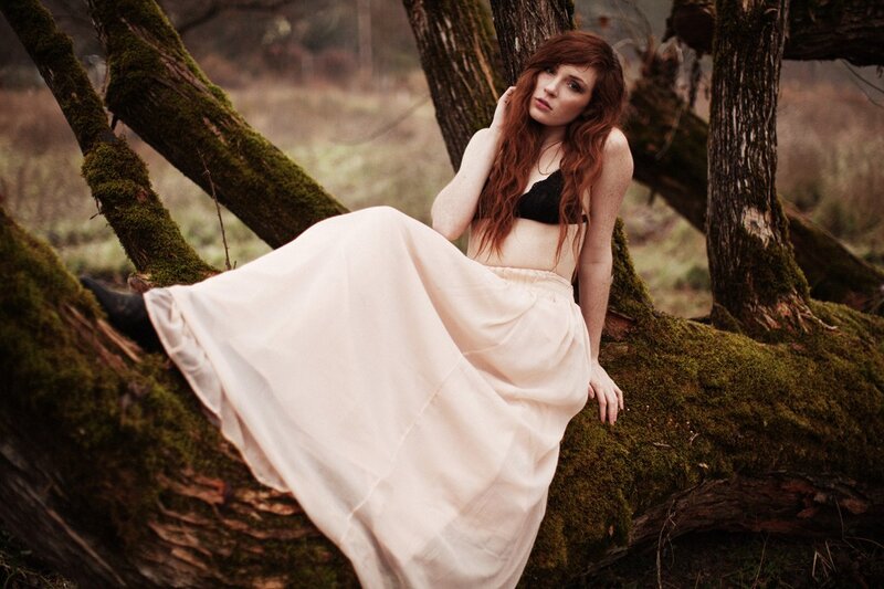 woman in forest on mossy log