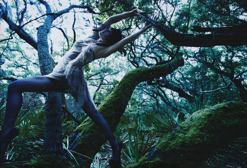 woman in forest reaching up