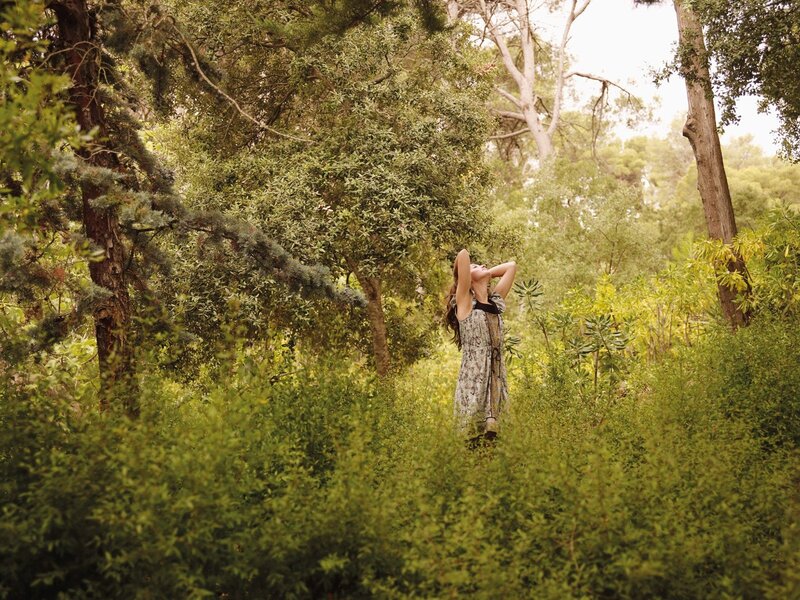 Woman in forest with arms raised