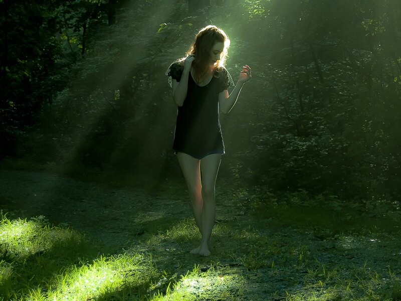 Woman in forest with sunbeams