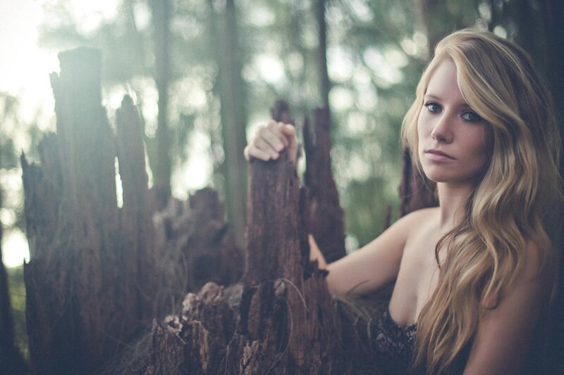 woman in forest with tree stump