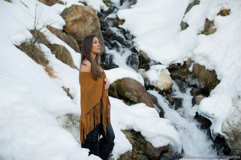 Woman in fringed poncho by stream