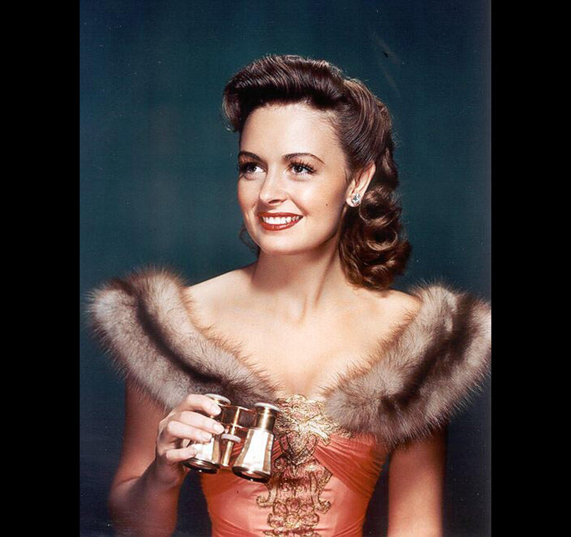Woman in fur stole holding binoculars