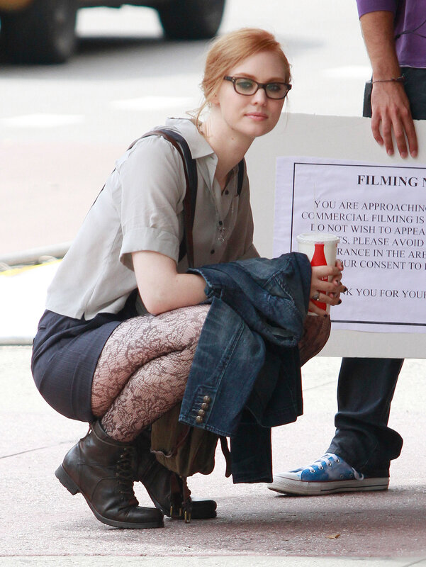 woman in glasses crouching on street