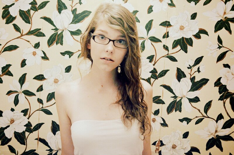 woman in glasses with floral wallpaper