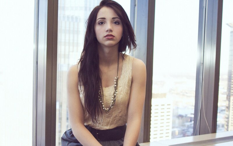woman in gold top by window