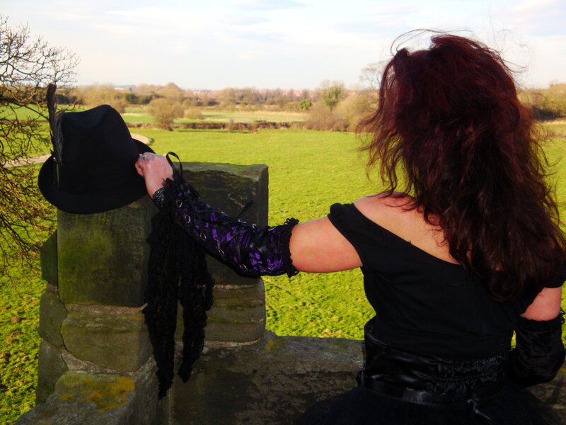 Woman in gothic attire at a stone wall