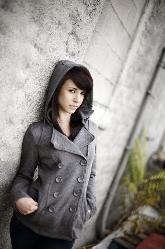 woman in gray coat leaning on wall