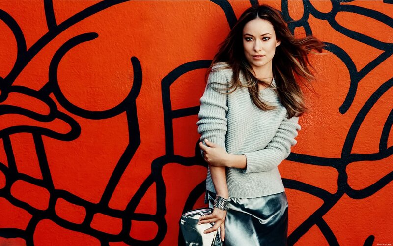 woman in gray sweater against orange wall