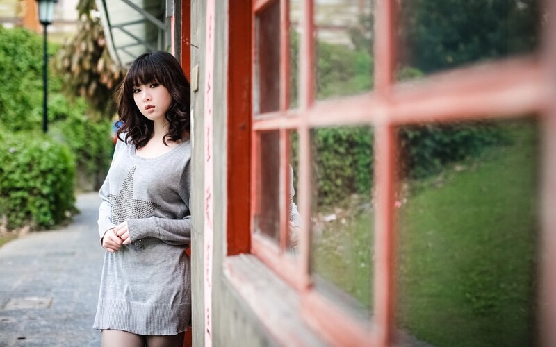 woman in gray sweater by window
