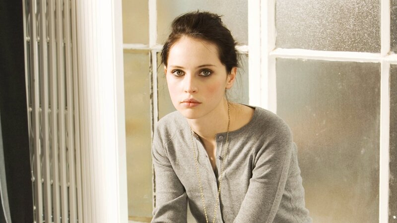 woman in gray sweater by window
