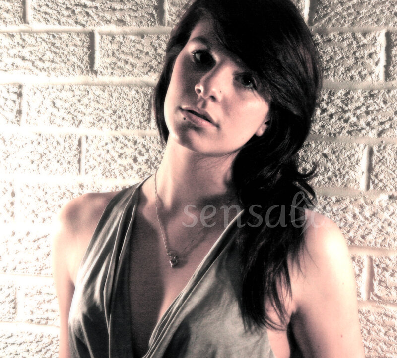 woman in gray top against brick wall