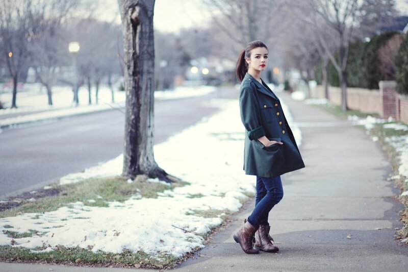 woman in green coat on sidewalk