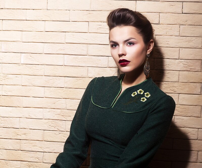 woman in green dress against brick wall