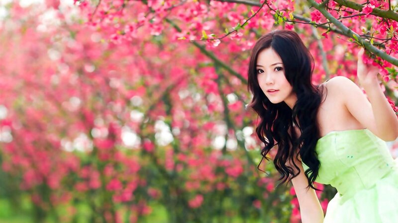 woman in green dress under blossoms