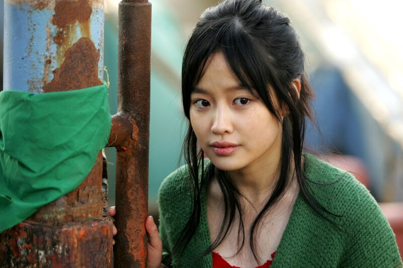 woman in green sweater by rusted pole