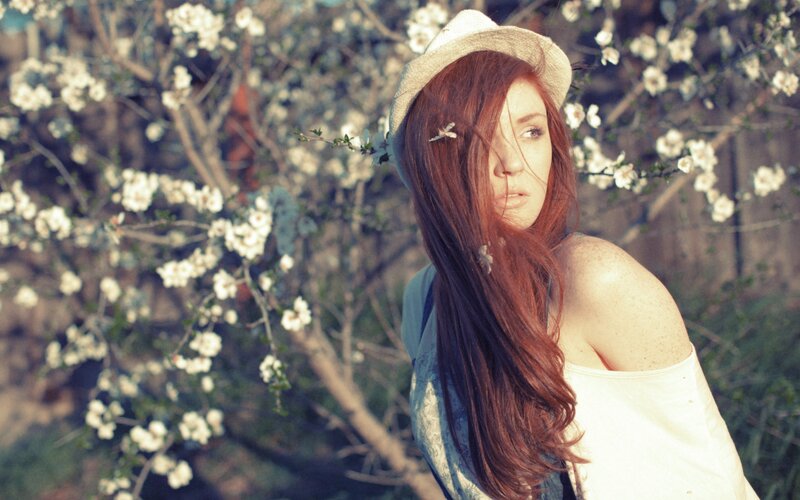 woman in hat among blossoms