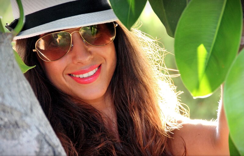 woman in hat and sunglasses smiling