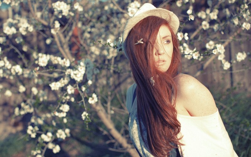 Woman in hat by blossoms