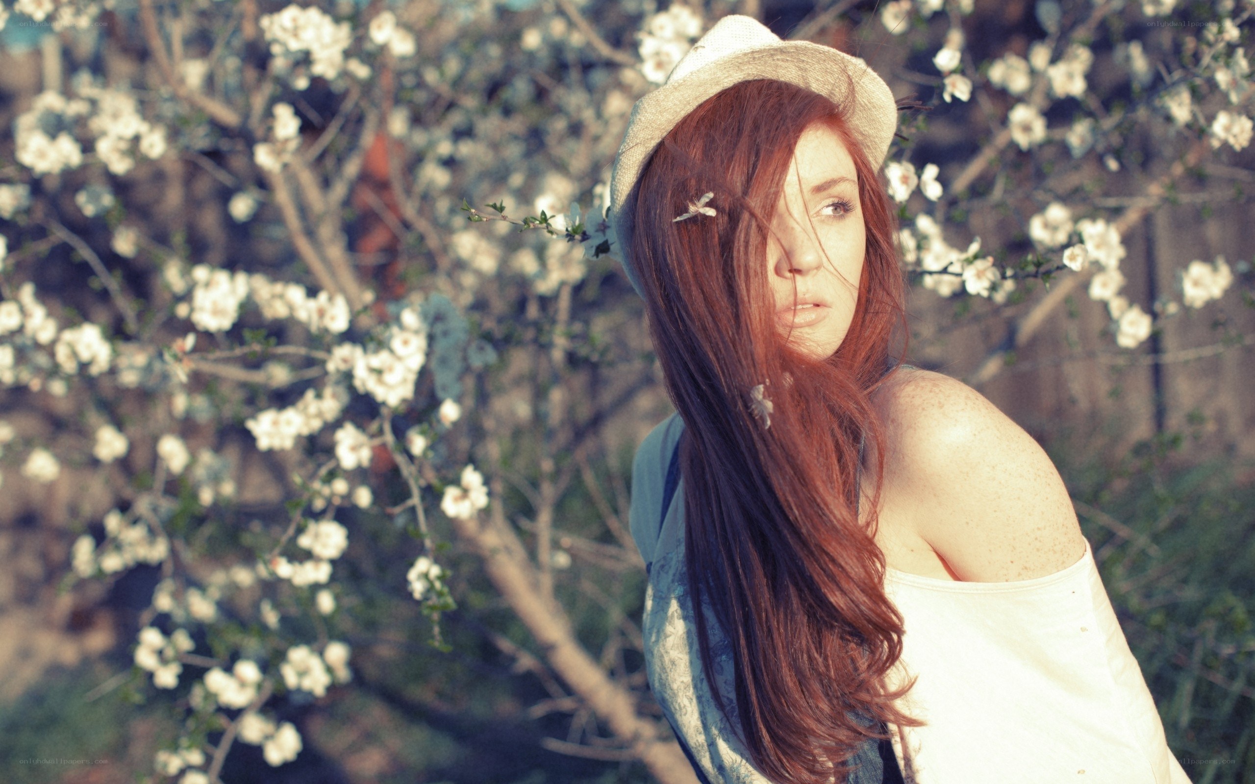 Woman in hat by blossoms