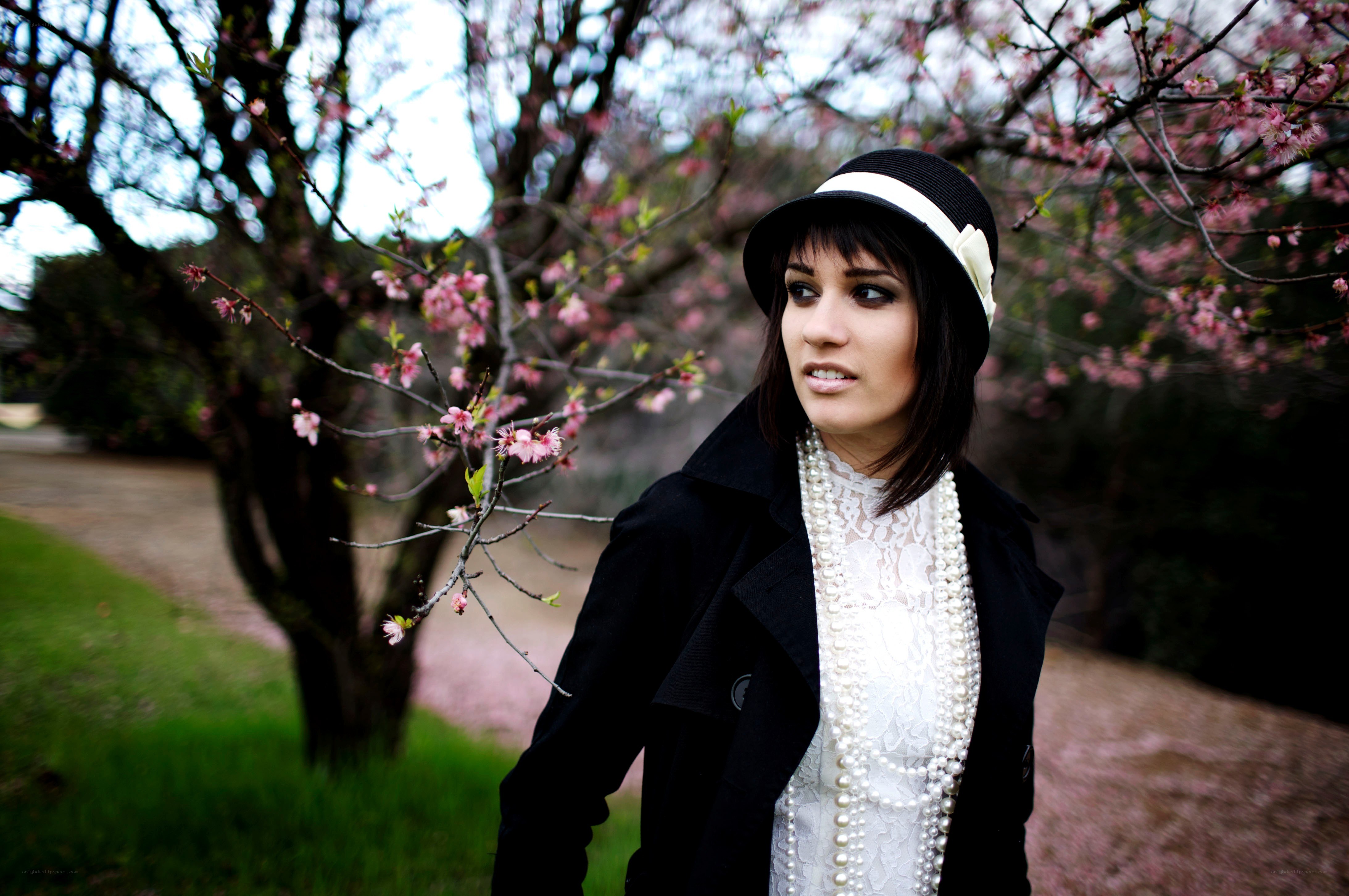 Woman in hat by cherry blossoms