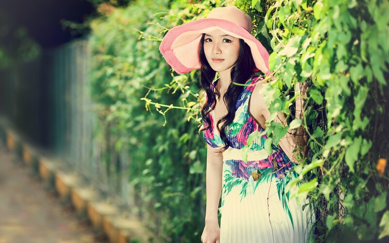 woman in hat by green vines