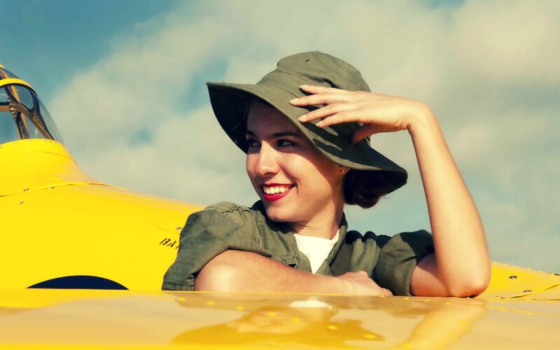 woman in hat by yellow plane