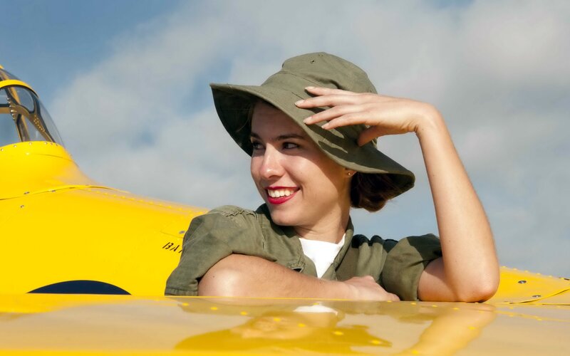 woman in hat by yellow plane