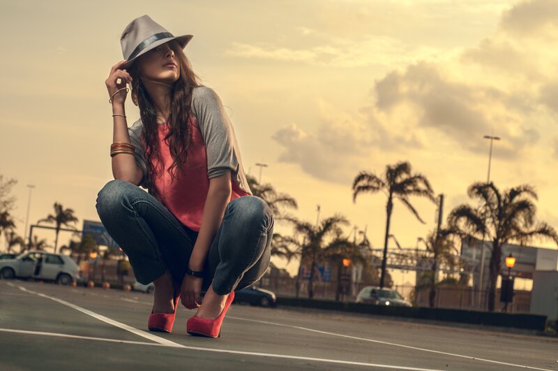 woman in hat crouching on street