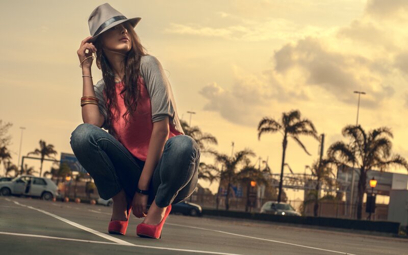 woman in hat crouching on street
