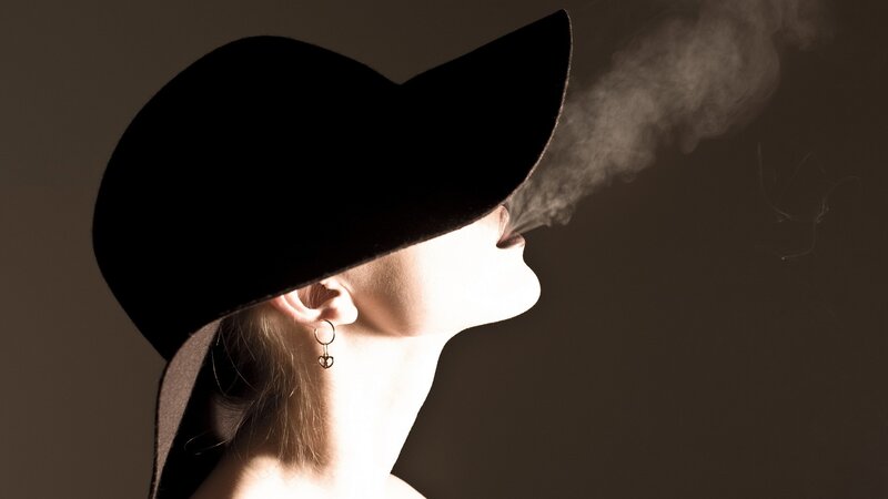 woman in hat exhaling smoke