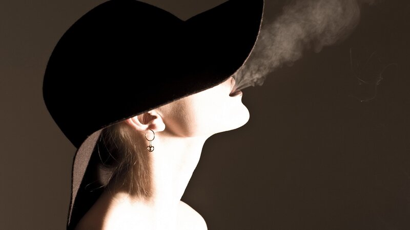 woman in hat exhaling smoke