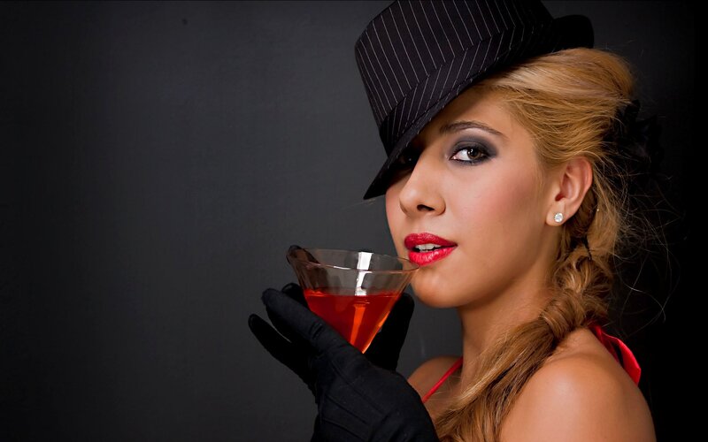 woman in hat holding cocktail