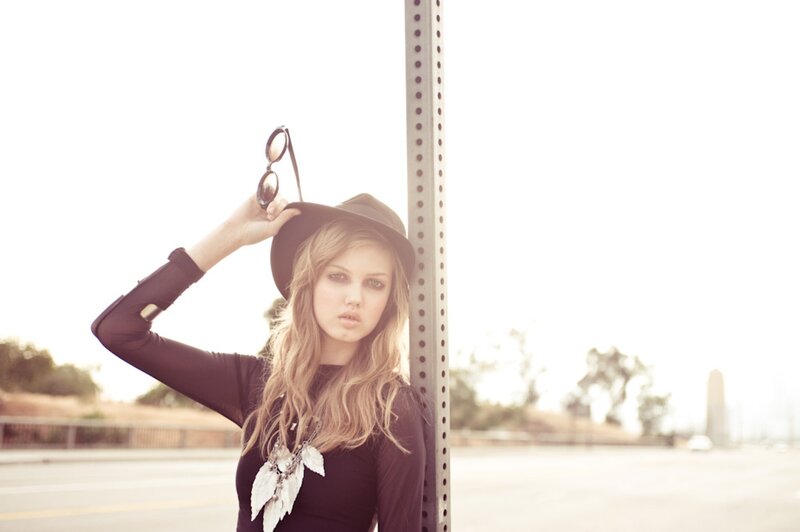 woman in hat holding sunglasses