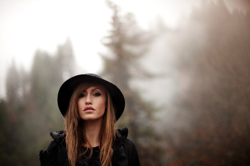 woman in hat in misty forest