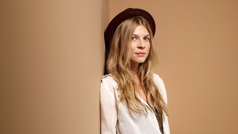 woman in hat leaning against wall