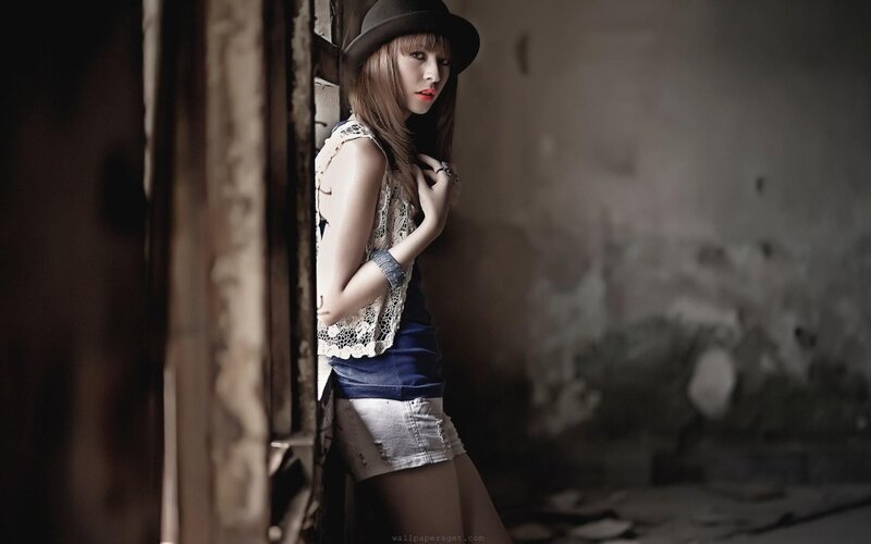 woman in hat leaning against wall