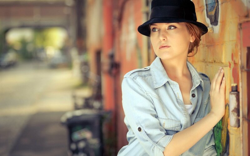woman in hat leaning on wall
